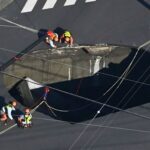 Swimming pool-sized sinkhole swallows truck on busy road, trapping driver